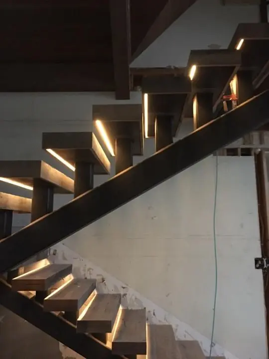 Floating staircase with lit wood treads on a steel stringer
