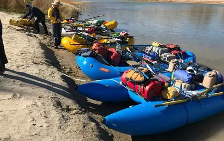 Loaded blue rafts pulled up on a river bank