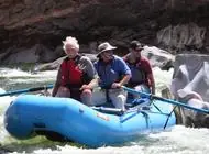 Three people running a rapid in a blue raft